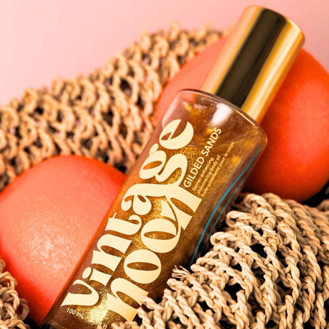 Vintage Noon shimmering body oil bottle styled with fresh blood oranges representing natural citrus scent