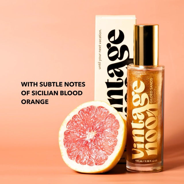 Gilded Sands body oil bottle and box displayed with Sicilian blood orange slice indicating subtle natural citrus fragrance